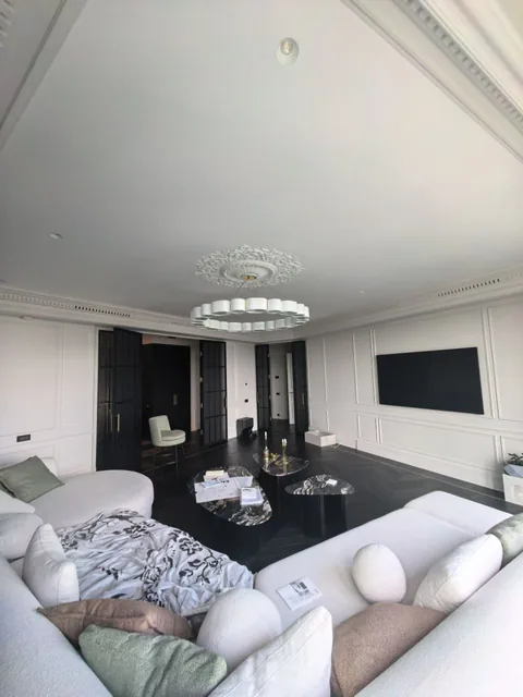 Гостиная квартиры 110 м² с диванной группой, тёмным полом и панорамными окнами